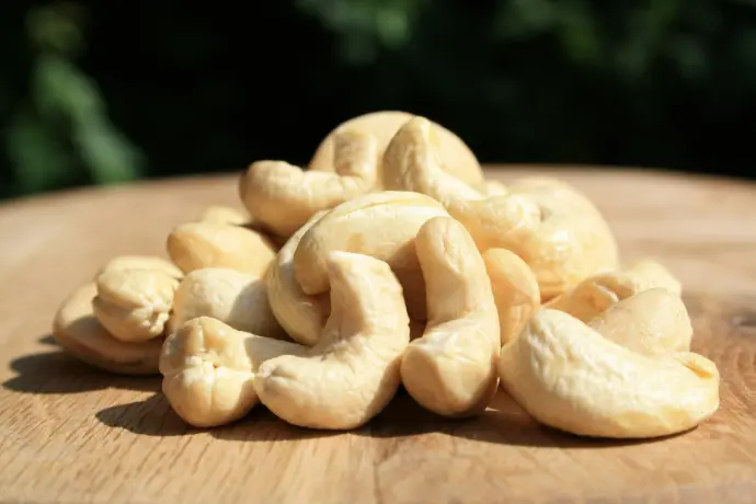 A pile of cashews sitting on top of a wooden table